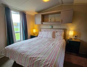a bedroom with a bed with a striped bedspread and a window at Pine Ridge a8 in Reighton