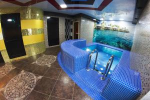 a bathroom with a blue tub with a swimming pool at Hotel Rus in Tolyatti