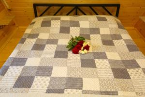 a quilt with a bouquet of flowers on a bed at Peradze Wine Cellar Vineyard Cottages in Khidistʼavi +27 photos