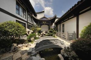 a building with a bridge in a garden at San Po Hotel in Fuzhou