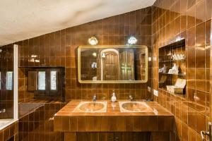 a brown tiled bathroom with two sinks and a mirror at El Revolt de Martís in Esponellá +31 photos