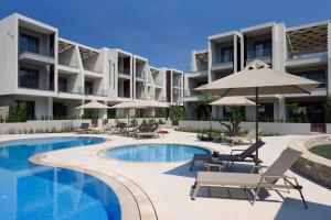 ニキティにあるDARION Apartmentsのリゾート(スイミングプール、椅子、パラソル付)