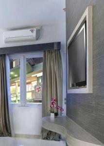 uma sala de estar com uma televisão e uma janela em Quest Hotel Balikpapan by ASTON em Balikpapan