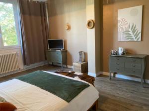 a bedroom with a bed and a television and a dresser at Cosy Er Lann Chambres d'Hôtes in Val Couesnon