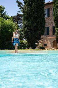 a woman in a blue dress standing next to a swimming pool at Tenuta Santa Trice in Riotorto