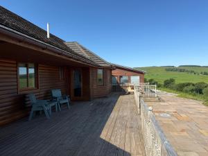 a house with a wooden deck with a bench on it at Auchenhill Lodge in Denny