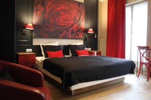 a room with a bed, chair and a painting on the wall at Hotel Roses in Strasbourg