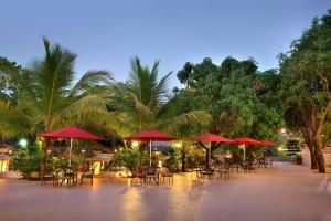 a patio with tables and chairs and red umbrellas at Villa San Lawrenz in Lonavala