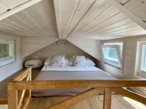 a bed in a tiny house with two windows at Leśne Siedlisko Wygonin in Wygonin