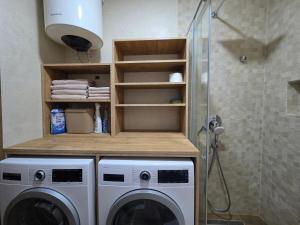 a washing machine in a bathroom next to a shower at Wildstone Krusi - Pool & Apartments 1 in Podgorica