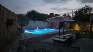a swimming pool with an umbrella and some chairs at Wildstone Krusi - Pool & Apartments 1 in Podgorica