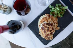 a plate of food on a table with a glass of wine at Hôtel - Restaurant U Santu Petru in Saint-Florent