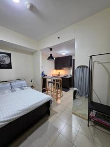 a bedroom with a bed and a kitchen with a table at Pioneerwoodlands Mandaluyong Studio Unit in Manila