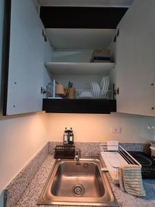 a kitchen counter with a sink and a shelf at Pioneerwoodlands Mandaluyong Studio Unit in Manila