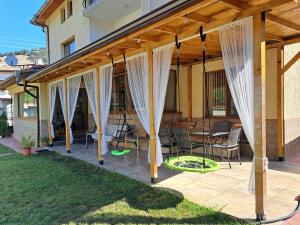 a wooden pergola with chairs and tables on a patio at Guest House Benita in Devin