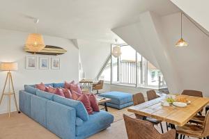 a living room with a blue couch and a table at Pentire Point - Coastal Penthouse, Beaches, River & Restaurants All Within Short Walk in Newquay +28 photos