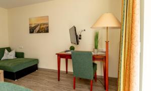 a room with a desk and a chair and a table with a lamp at Apartment Juwel in Bensersiel