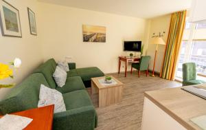 a living room with a green couch and a table at Apartment Juwel in Bensersiel