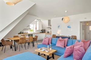 a living room with a blue couch and a table at Pentire Point - Coastal Penthouse, Beaches, River & Restaurants All Within Short Walk in Newquay
