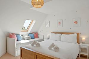 a white bedroom with two beds and a window at Pentire Point - Coastal Penthouse, Beaches, River & Restaurants All Within Short Walk in Newquay