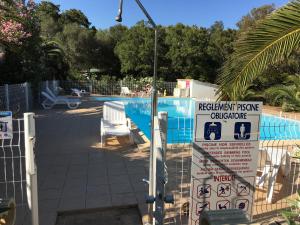 a swimming pool with a sign next to a fence at Camping Pezza Cardo in Porto-Vecchio