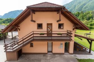 a house with a balcony and mountains in the background at Apartma Jernej in Bovec