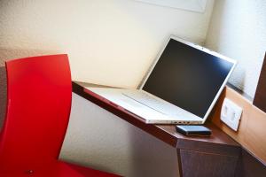 un ordinateur portable installé au-dessus d'un bureau en bois dans l'établissement Premiere Classe Montpellier Sud Lattes, à Lattes