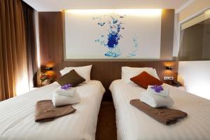 two beds in a hotel room with towels on them at 41 Suite Bangkok in Bangkok