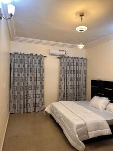 a bedroom with a bed and two curtains at Home in Abuja Municipal Area Council in Abuja