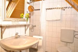 a white bathroom with a sink and a toilet at Weingasthof Zum weißen Roß in Osthofen