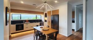 a kitchen with a dining room table and a chandelier at Piwakawaka Lodge Kerikeri - Incredible waterfront views in Kerikeri