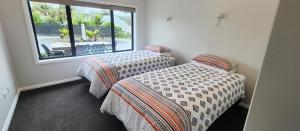 two twin beds in a room with a window at Piwakawaka Lodge Kerikeri - Incredible waterfront views in Kerikeri