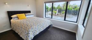 een slaapkamer met een bed en een groot raam bij Piwakawaka Lodge Kerikeri - Incredible waterfront views in Kerikeri +10 foto's