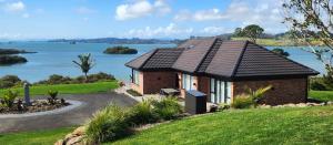 a brick house with a view of the water at Piwakawaka Lodge Kerikeri - Incredible waterfront views in Kerikeri