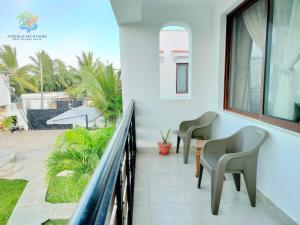 a balcony with chairs and a table and a window at 1 bedroom suite Diani in Ukunda Airport