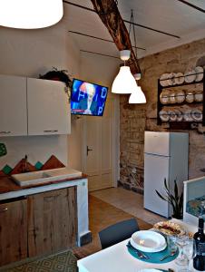 a kitchen with a white refrigerator and a tv on the wall at Nicola appartamento in Giba