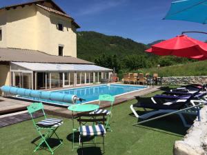 a swimming pool with chairs and a red umbrella at Les 2 Alpes in Puget-Théniers