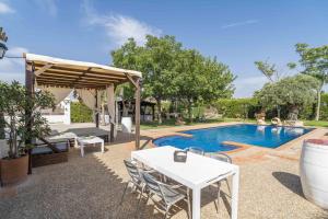 Un patio con mesa y sillas y una piscina. en Casa Rural Carula, en La Puebla de Cazalla