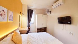 a bedroom with a bed and a tv on the wall at B House in Ho Chi Minh City