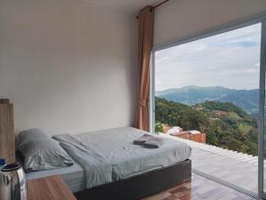 a bedroom with a bed and a large window at ภูศิโยน ม่อนแจ่ม in Mon Jam
