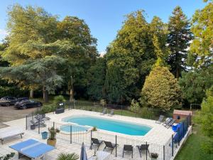 a swimming pool with chairs and a table and a picnic table at Cosy Er Lann Gîte Séquoïa in Val Couesnon