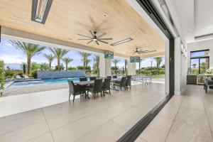a patio with a table and chairs and a pool at Palm Villa- Luxury 7 Bed, Pickleball, Volleyball, Golf in Indio