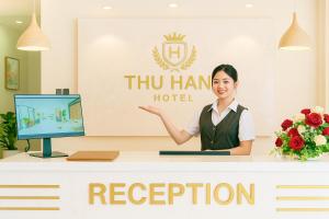 a woman is standing behind a reception desk in a hotel at Nhà Nghỉ Thu Hằng 1 in Hà Ðông