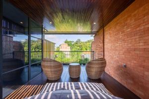 a balcony with two wicker chairs on a brick wall at Baliris Canggu Villa by Betterplace in Tumbak Bayuh