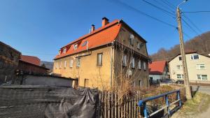 an old house with a red roof and a fence at Sowi Przystanek in Pieszyce