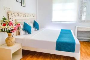 un letto bianco in una stanza con un vaso di fiori di Stylish Poolside 2BHK Near Candolim to Eat, Chill, Party Nearby a Candolim Altre 16 foto
