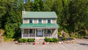 a house with a green roof and a yard at Lake and Pool Table - Au Pied du Lac in Labelle