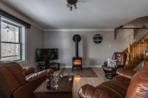 a living room with leather furniture and a wood stove at Lake and Pool Table - Au Pied du Lac in Labelle