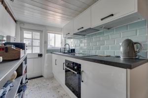 eine Küche mit weißen Schränken und blauen Fliesen in der Unterkunft Winter Cottage, Clare in Clare