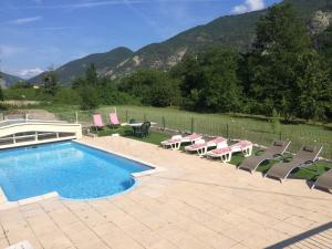 a swimming pool with chairs and a table and mountains at Les 2 Alpes in Puget-Théniers